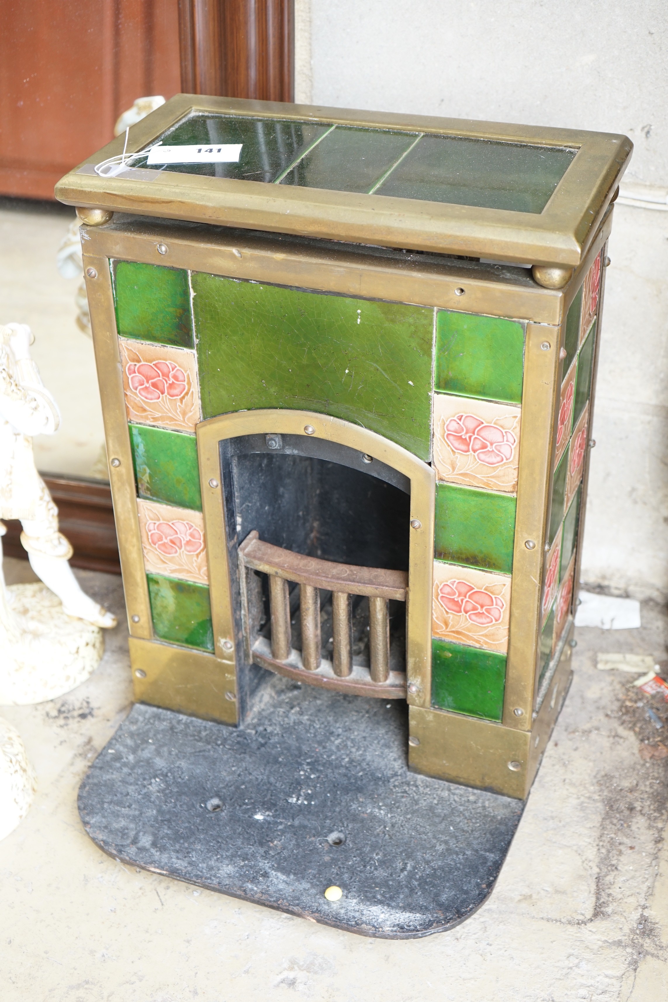 An Art Nouveau tiled brass mounted small cast iron fireplace, width 39cm, height 57cm
